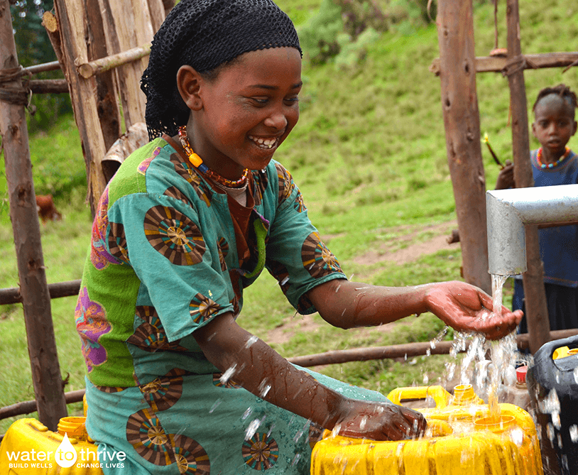 photo of african girl enjoying water from a pipe