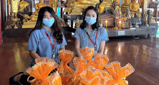 photo of two women in front of bags of money and household items